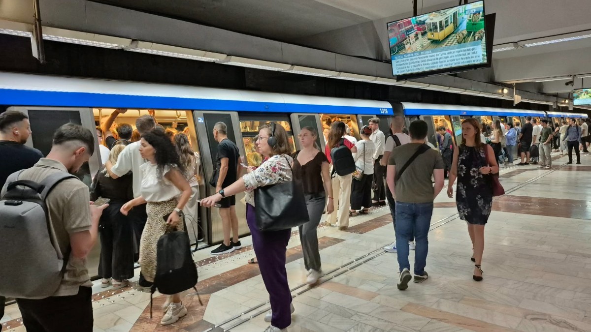 Zeci de oameni care stau pe peronul unei stații de metrou din București 