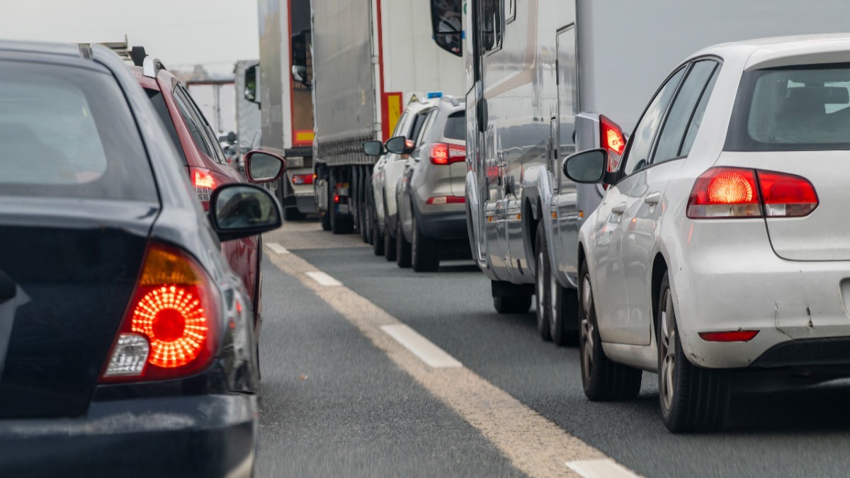 O coloană aglomerată de autoturisme și vehicule mari de marfă prinse într-un ambuteiaj pe mai multe benzi ale unei șosele.