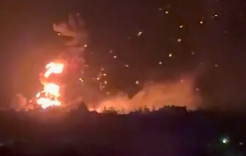 O coloană verticală masivă de flăcări se ridică de la orizont, depășind înălțimea structurilor indistincte de la sol. Numeroase fragmente sunt aruncate în aer deasupra focului principal, Kiev, 11 septembrie 2026
