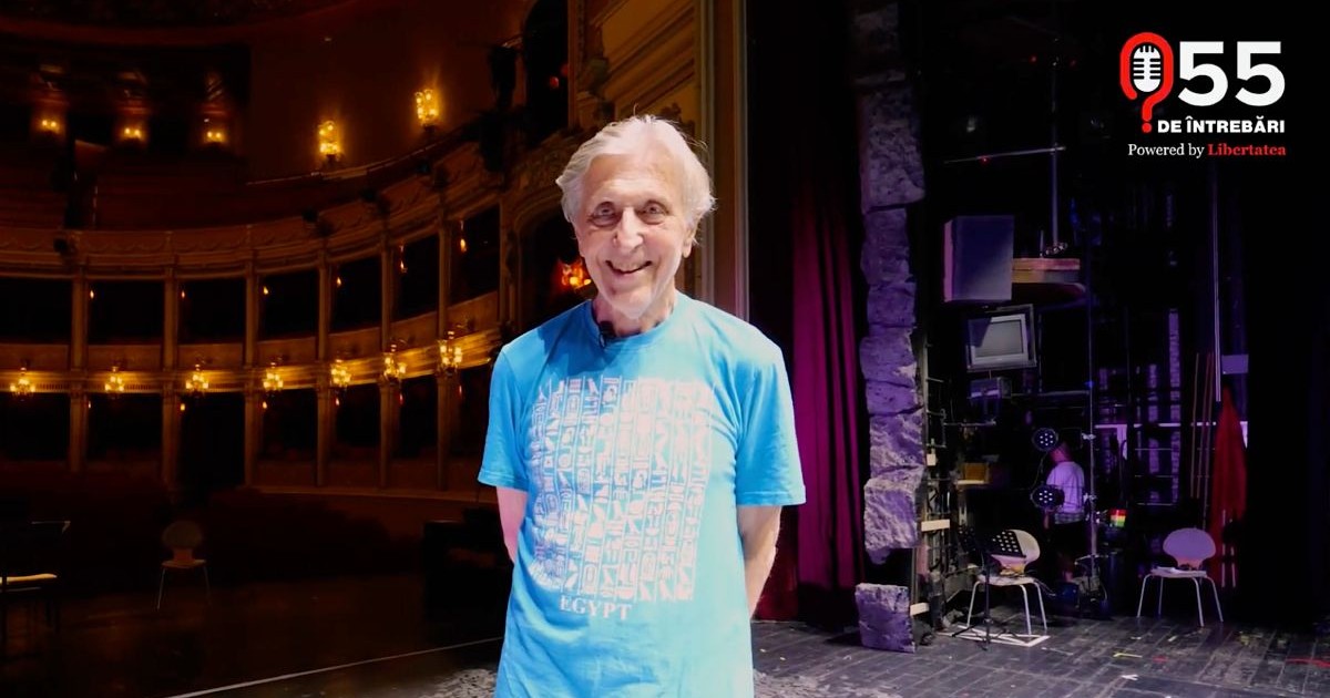 Andrei Șerban, pe scena unui teatru, îmbrăcat cu un tricou albastru cu un scris alb.