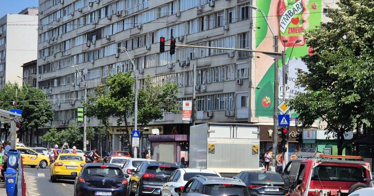 O intersecție aglomerată din București, mașinile stau la coadă la un semafor care este roșu