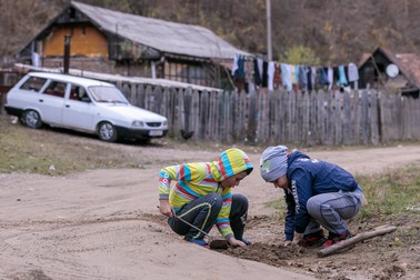 Doi copii din colonia de pe strada Libertății se joacă de-a minerii