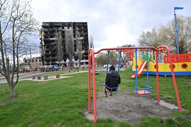 Un tânăr privește din leagăn ruina unui bloc rezidențial distrus de bombardamente, în Borodianka, pe 17 aprilie 2022 | Foto: Profimedia