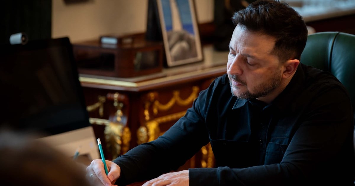 Președintele Ucrainei, Volodimir Zelenski, în timp ce semnează un document la biroul său