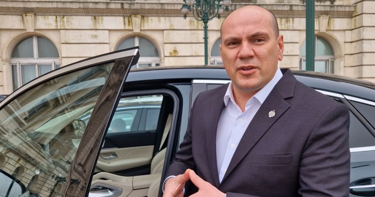 Deputatul Mihai Caragață, îmbrăcat la costum, în timp ce stă lângă mașina Mercedes GLE în fața Parlamentului