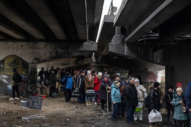 Oameni care așteaptă sub podul distrus din Irpin să fie evacuați către ieșirea din oraș, 7 martie 2022. Foto: EPA