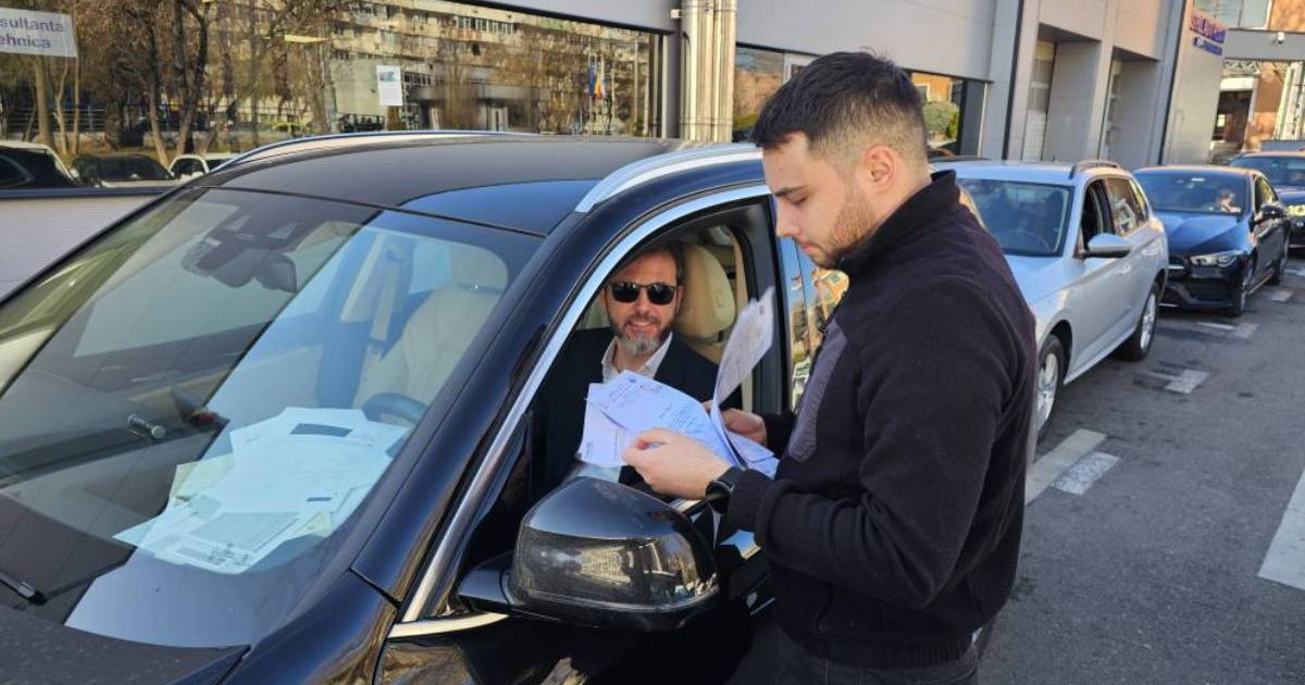 mai multe masini in linie pentru inspectia rar. un barbat tine in mana cateva documente pentru inspectie, in masina se afla un sofer