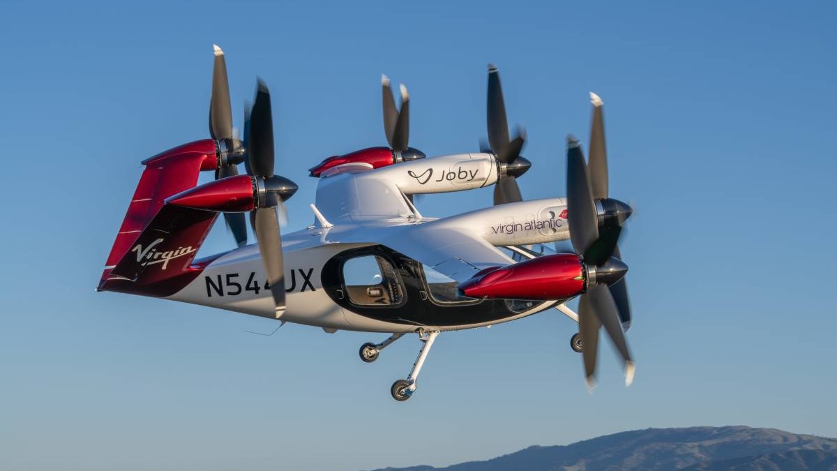 elicopter electric cu fuselaj rosu cu alb, motoare cu sase elicii montate pe aripi și pe coada pentru decolarea și aterizarea verticală