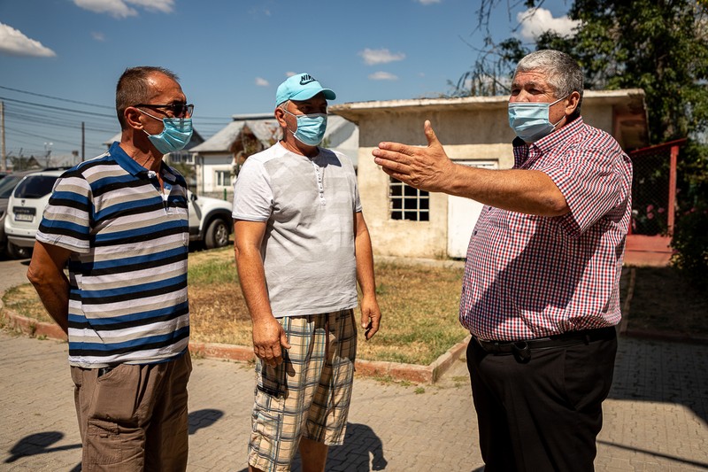 Doi săteni ascultă explicaţiile primarului