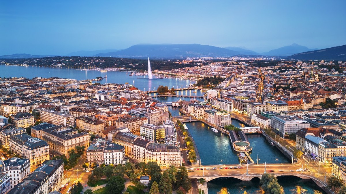 Vedere panoramică asupra orașului Geneva, Elveția, spre fântâna Jet d'Eau din Lacul Geneva, la apus.